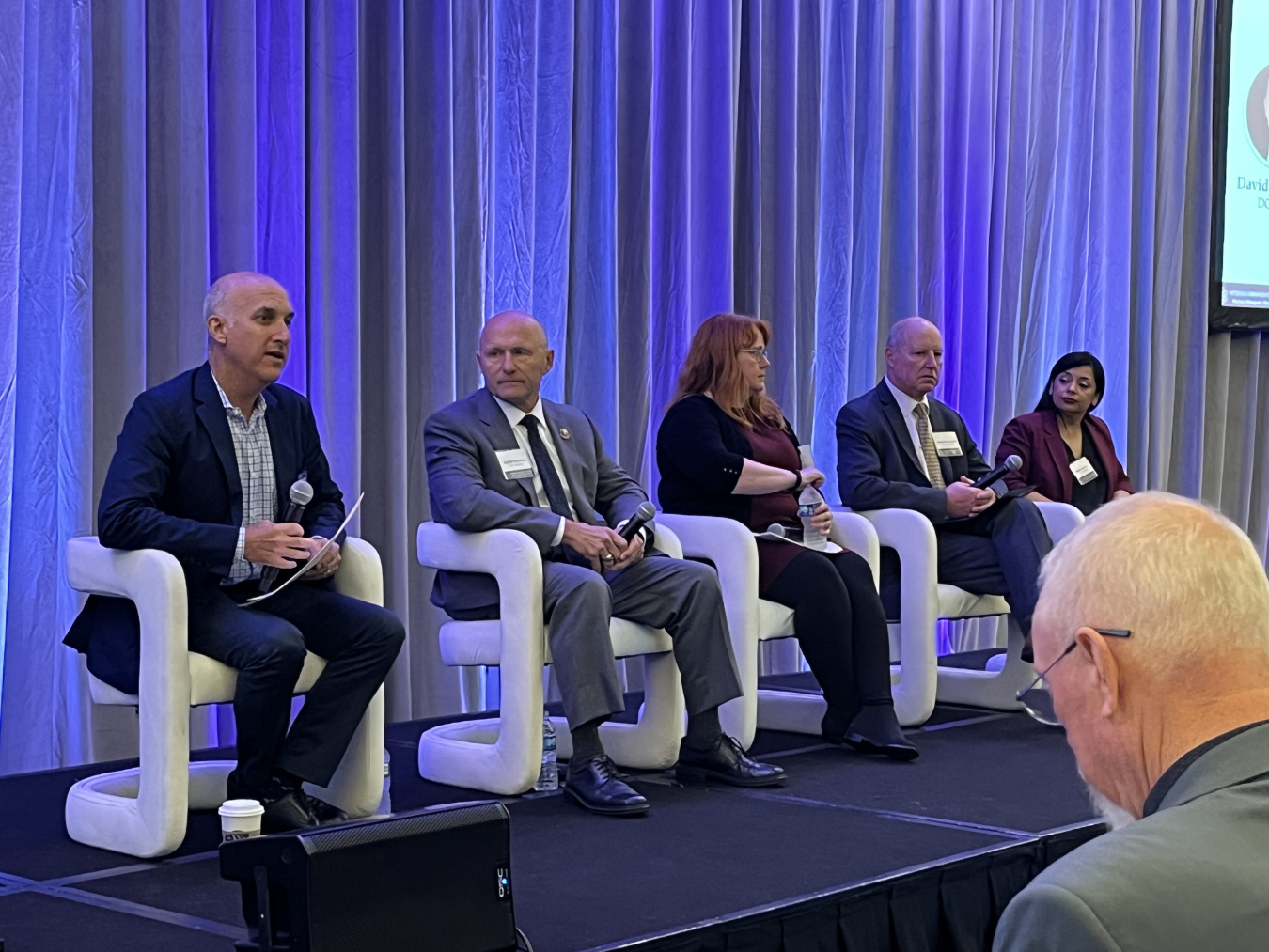 DOE Leadership and Officials sit on stage during a panel at a conference