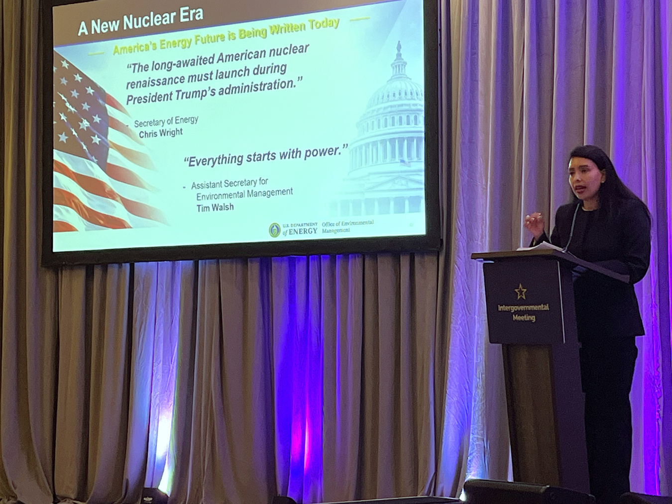 DOE Official standing behind a podium giving a presentation at a conference 