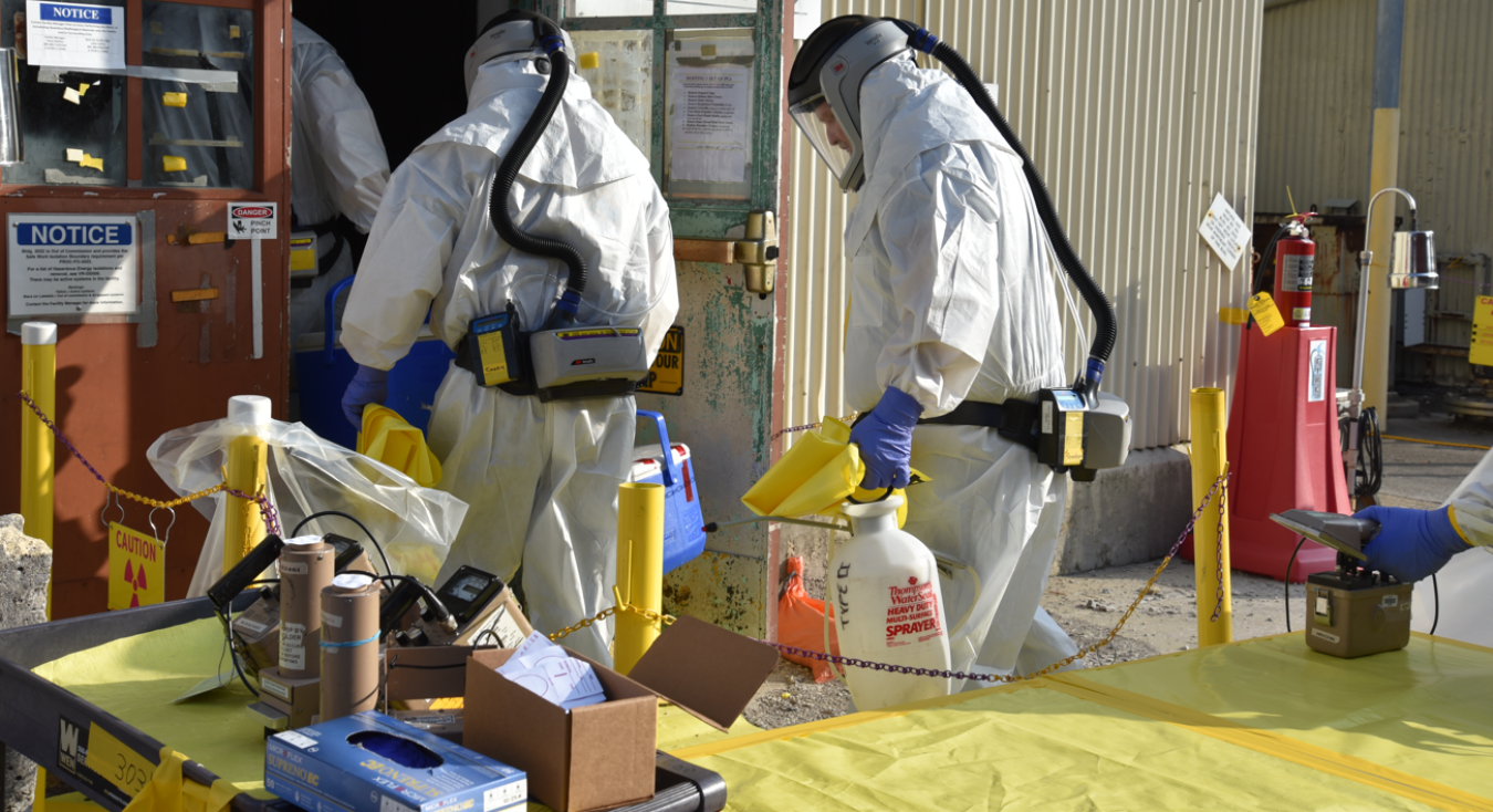 Employees in protective gear working to prepare a building for deactivation 
