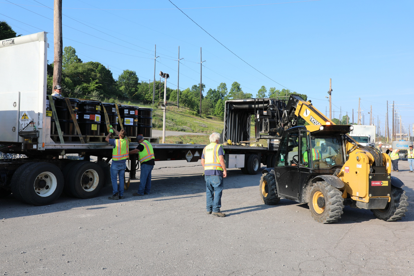 Construction vehicles loading shipments of waste containers onto a truck
