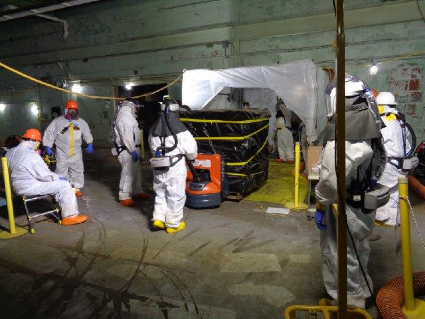 Employees in hazmat suits removing containers at the Oak Ridge Site