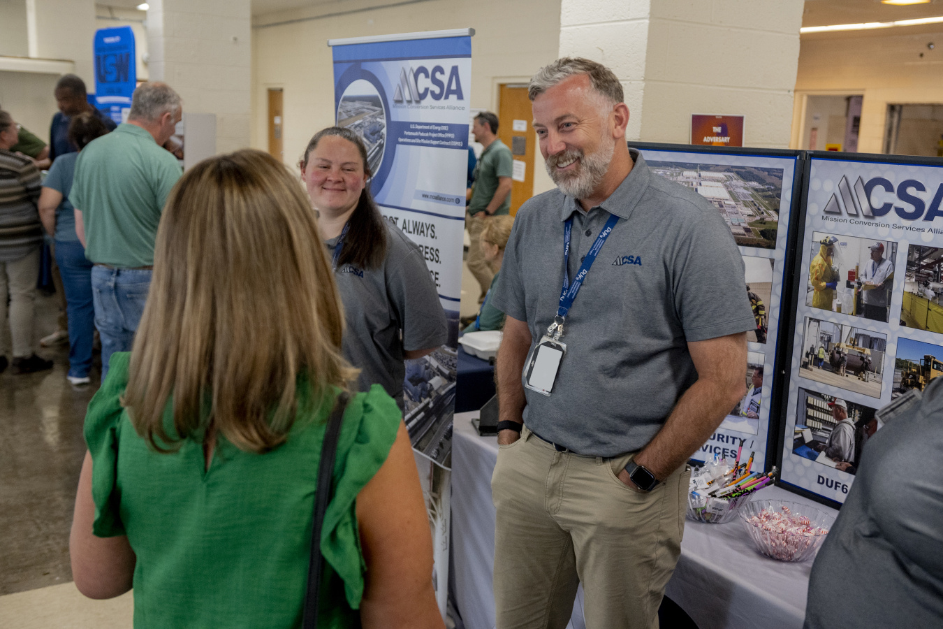 Employees running a booth at a conference speak to attendees 