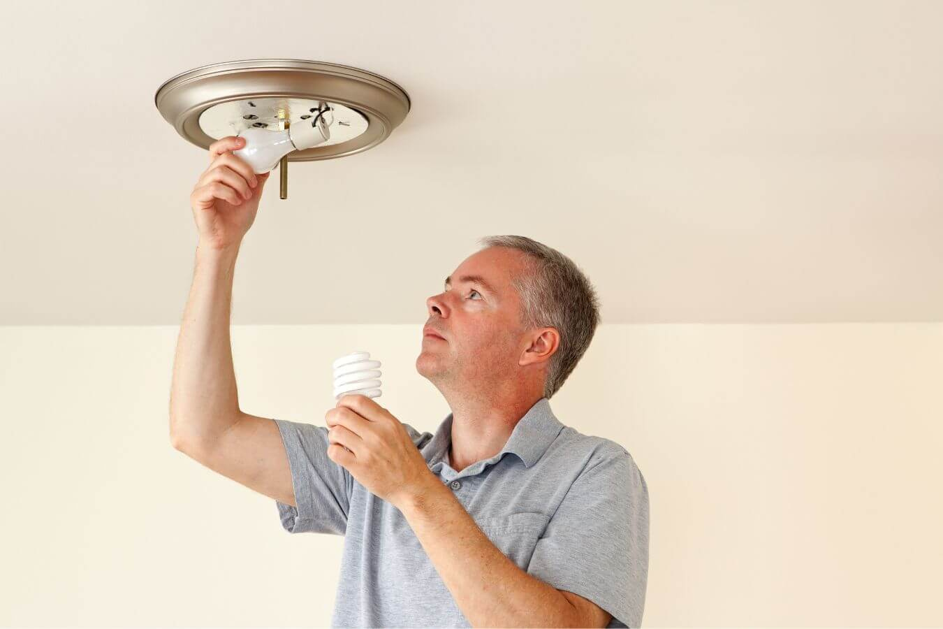 Man changing a light bulb in a mounted fixture