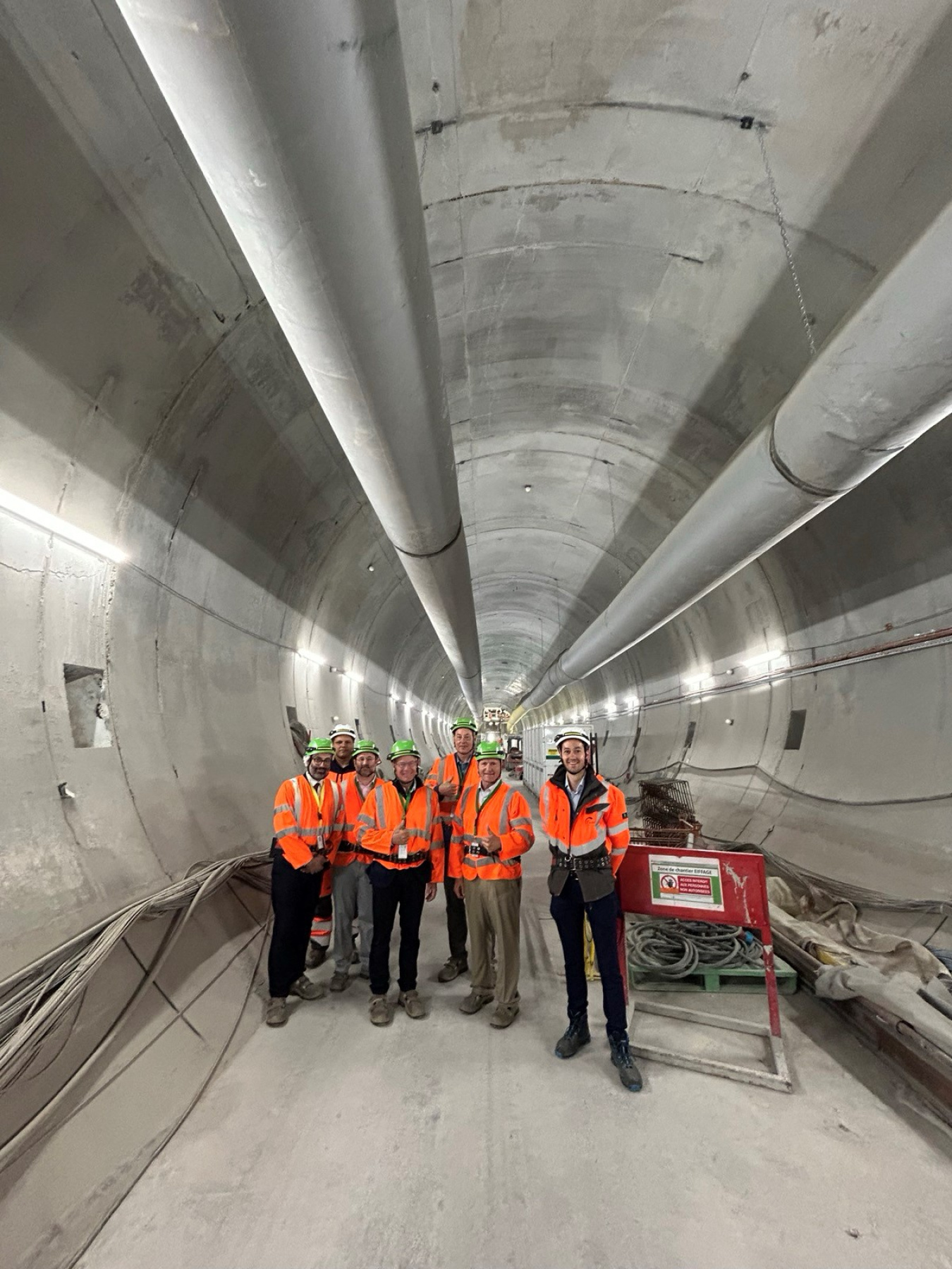 A group of people in orange safety jackets tour an underground lab