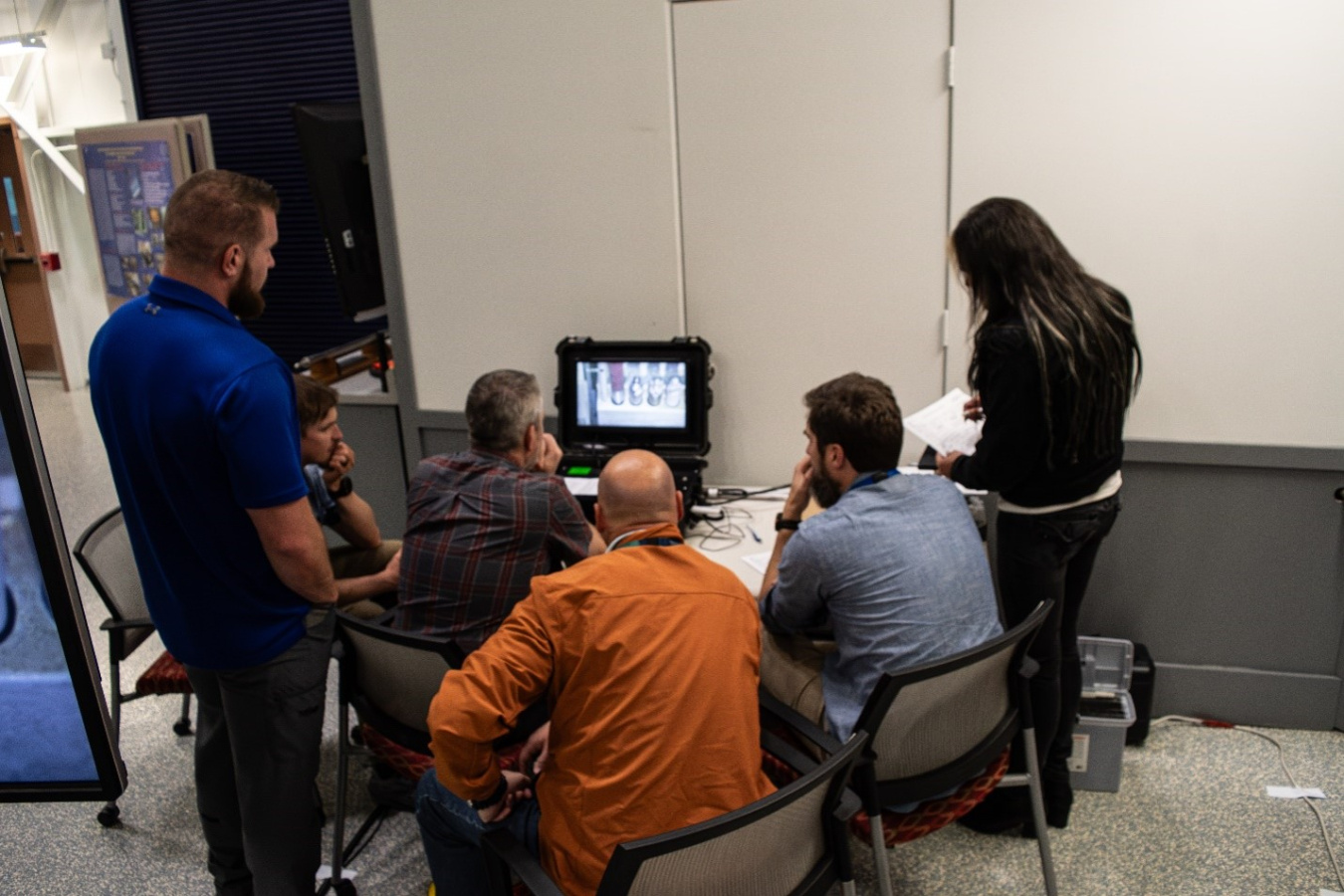 A group of professionals looking a monitor screen