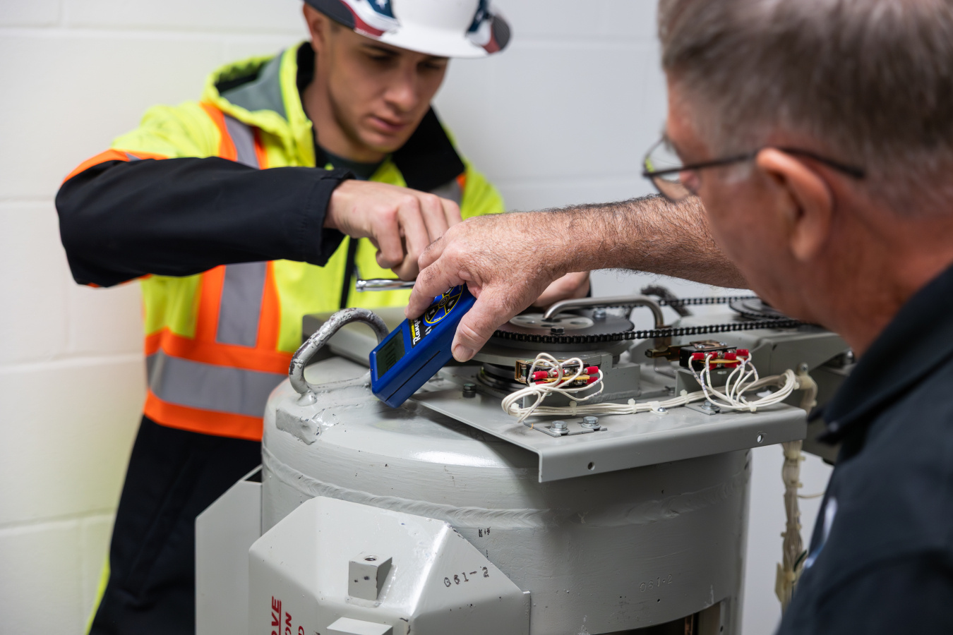 Two men take radiation readings on a dismantled cesium irradiator before removing it.