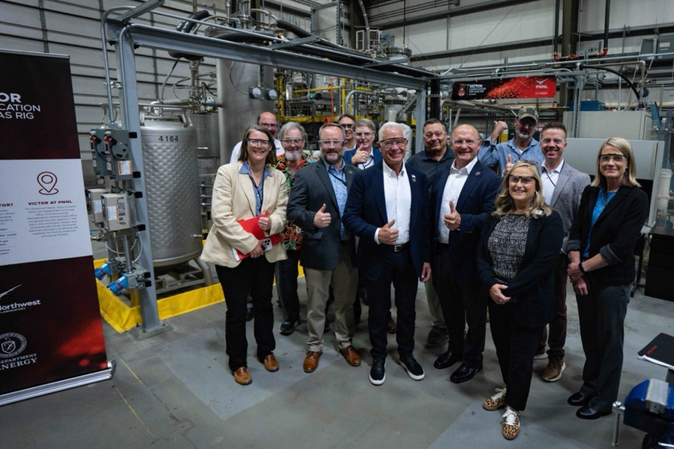 A group of DOE and PNNL employees pose for a photo in a laboratory building 