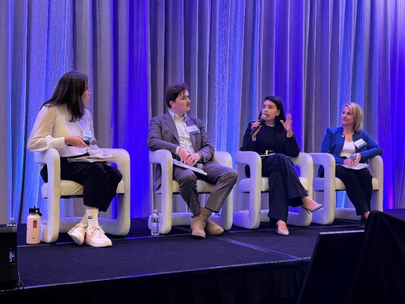 Four professionals sitting in chairs on stage participating in a panel discussion