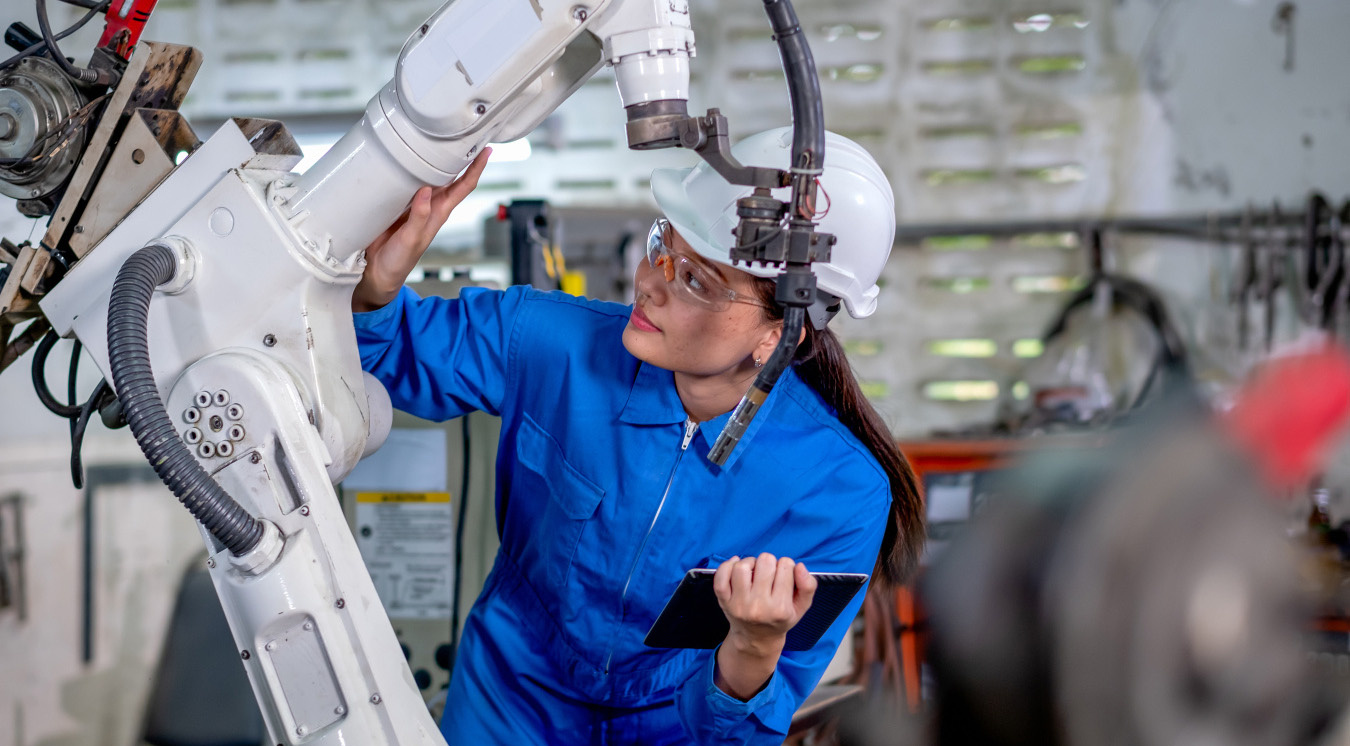 An engineer inspects an industrial robotic arm.