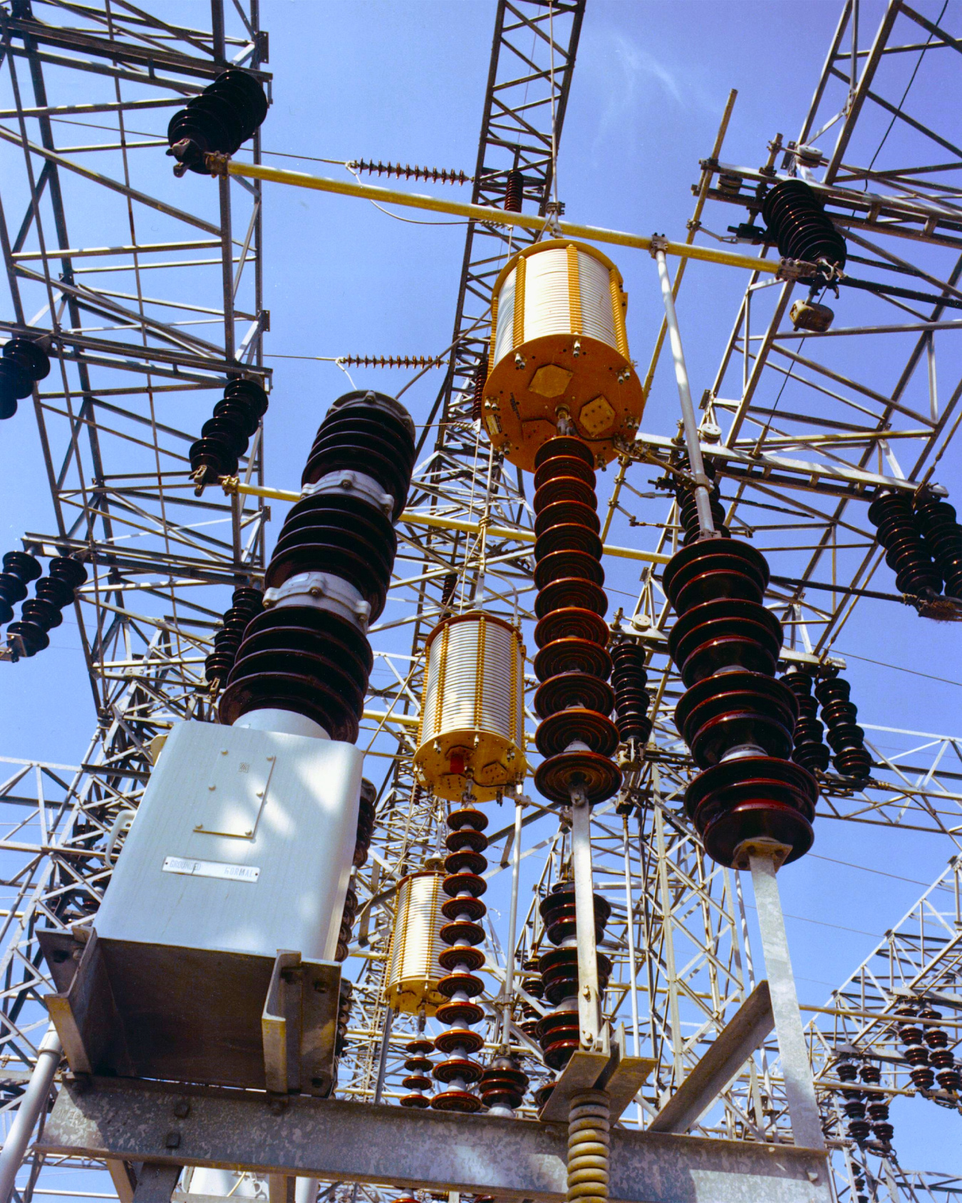 Electrical substation with high-voltage transformers, insulators, and switchgear connected by overhead transmission equipment.