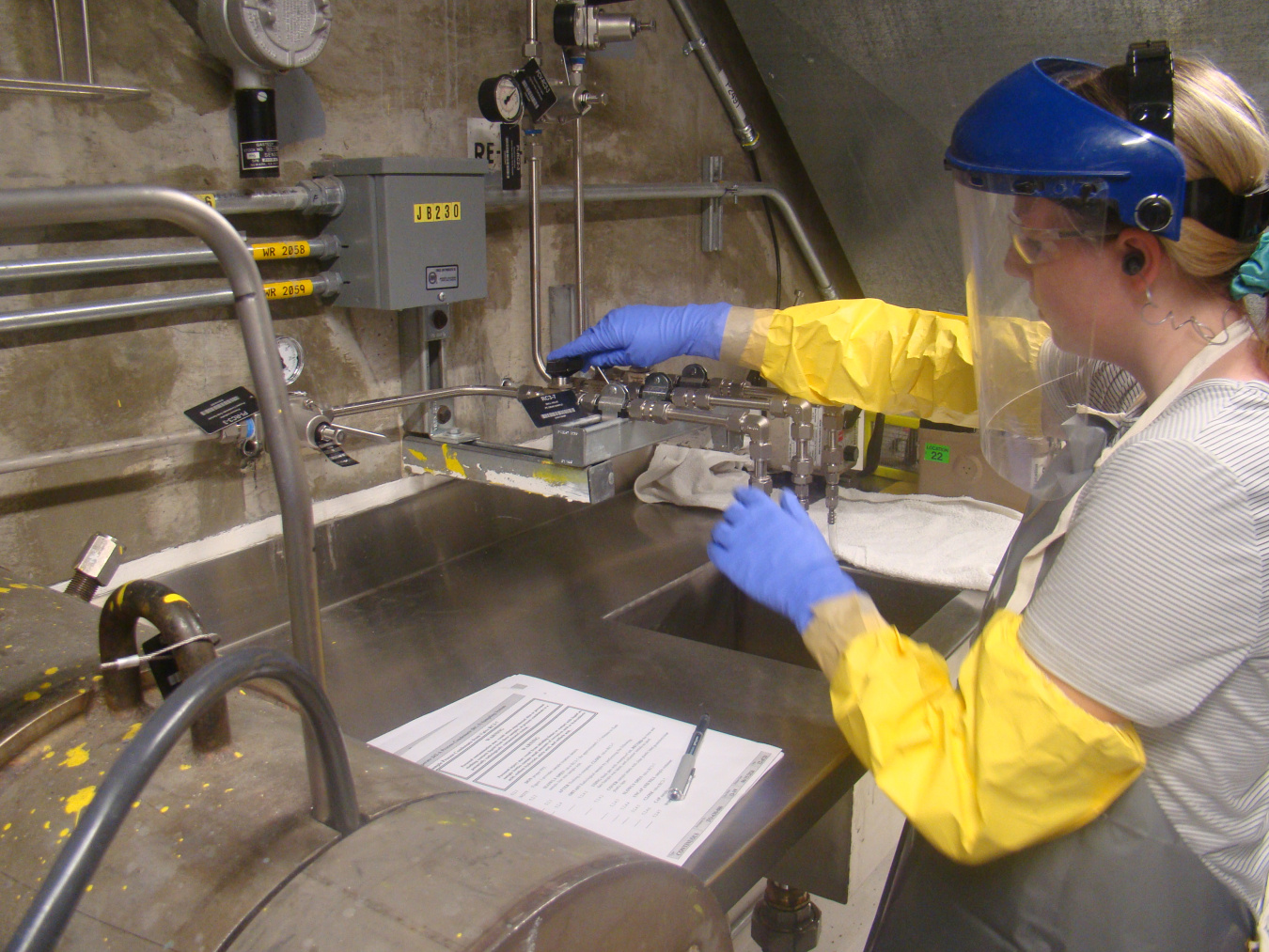 An employee in safety gear holding a sample at a laboratory table