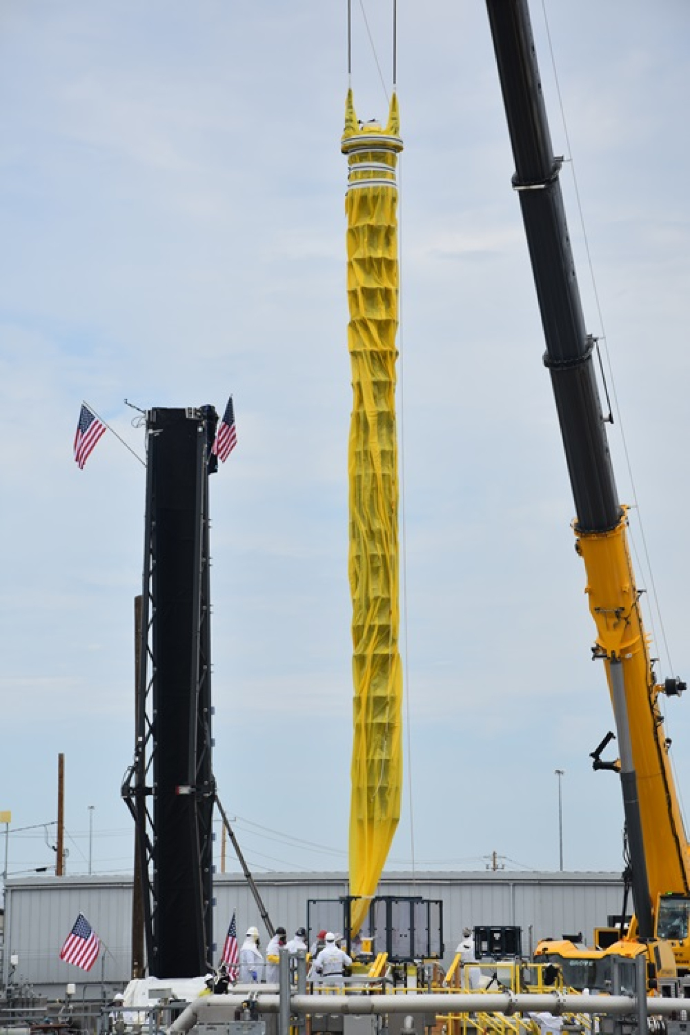 A large yellow tank mixer being lowered by a large crane