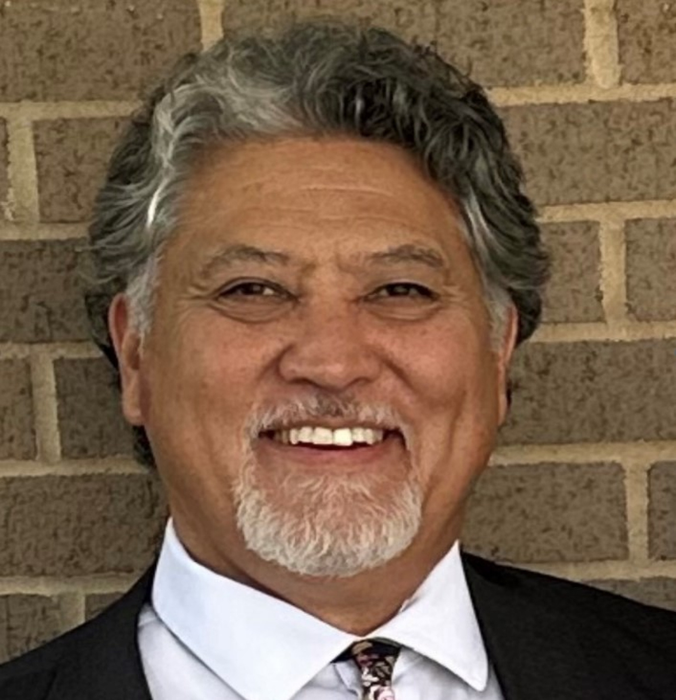 A headshot of a man in a suit smiling for a photo