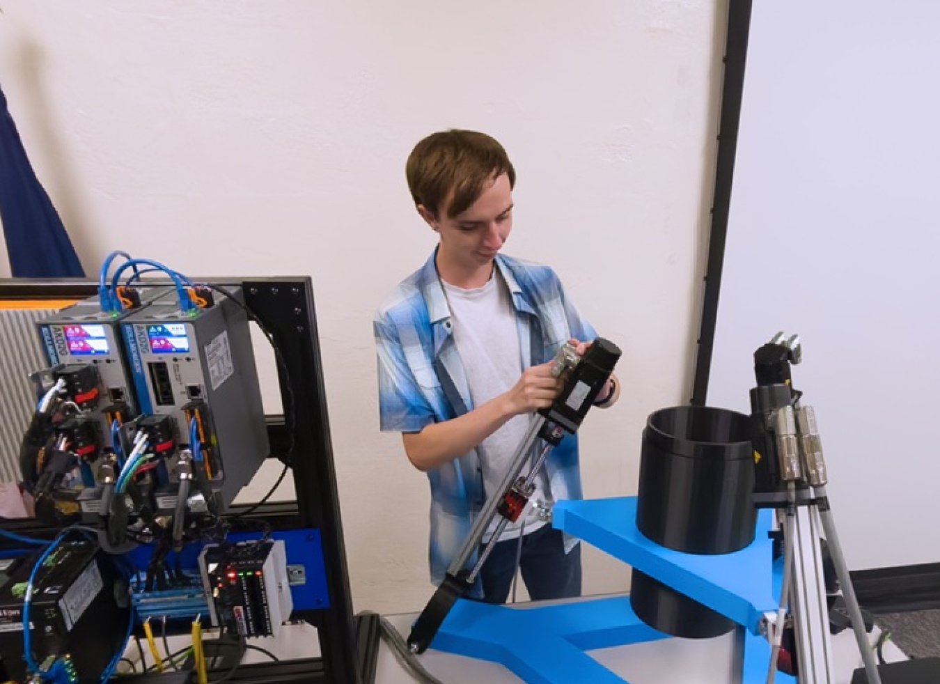 An intern at the Idaho site working with a mock-up system that includes metal tubes and computer systems with lots of wires