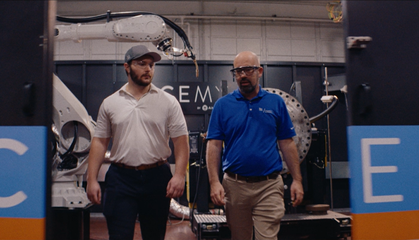 Curt Jawdy and an intern walk in front of a 3D metal  printing machine