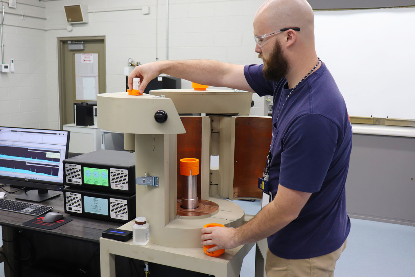 A man wearing safety glasses working on laboratory equipment at the Oak Ridge National Lab