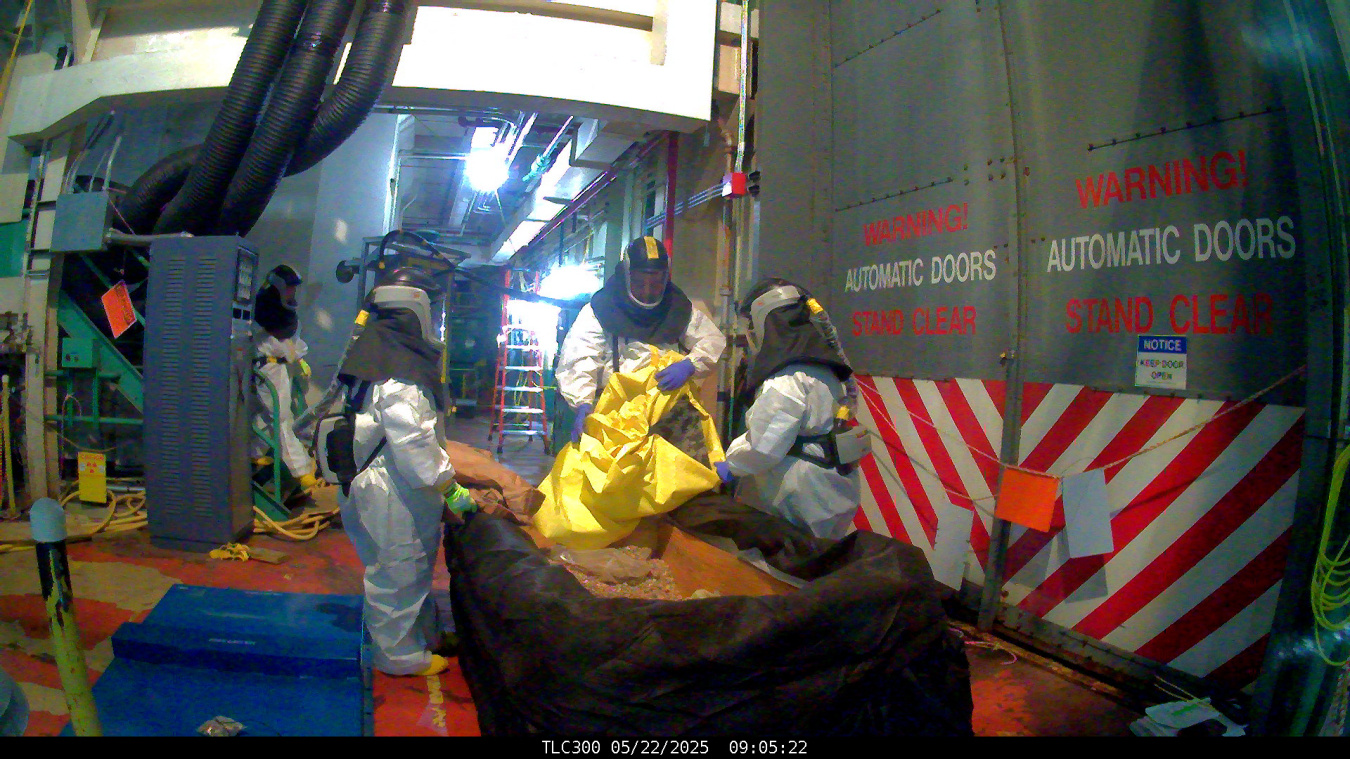 Employees in hazmat suits working inside a facility building working to remove lead
