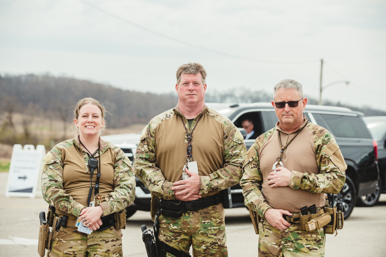 Three protective force employees in camouflage uniforms pose for a photo