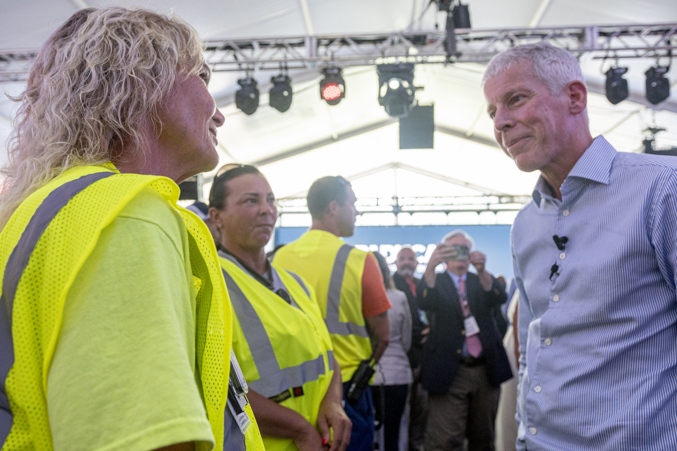 The DOE Secretary speaks with professionals in yellow safety vests at an event