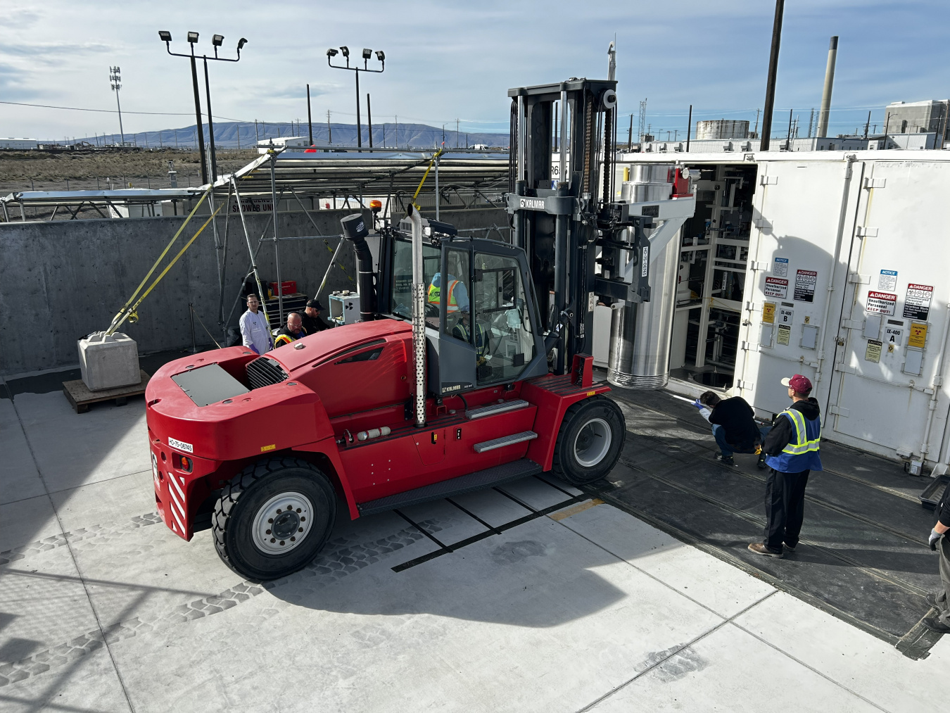 A large red construction vehicle with employees around it outside at the Hanford site