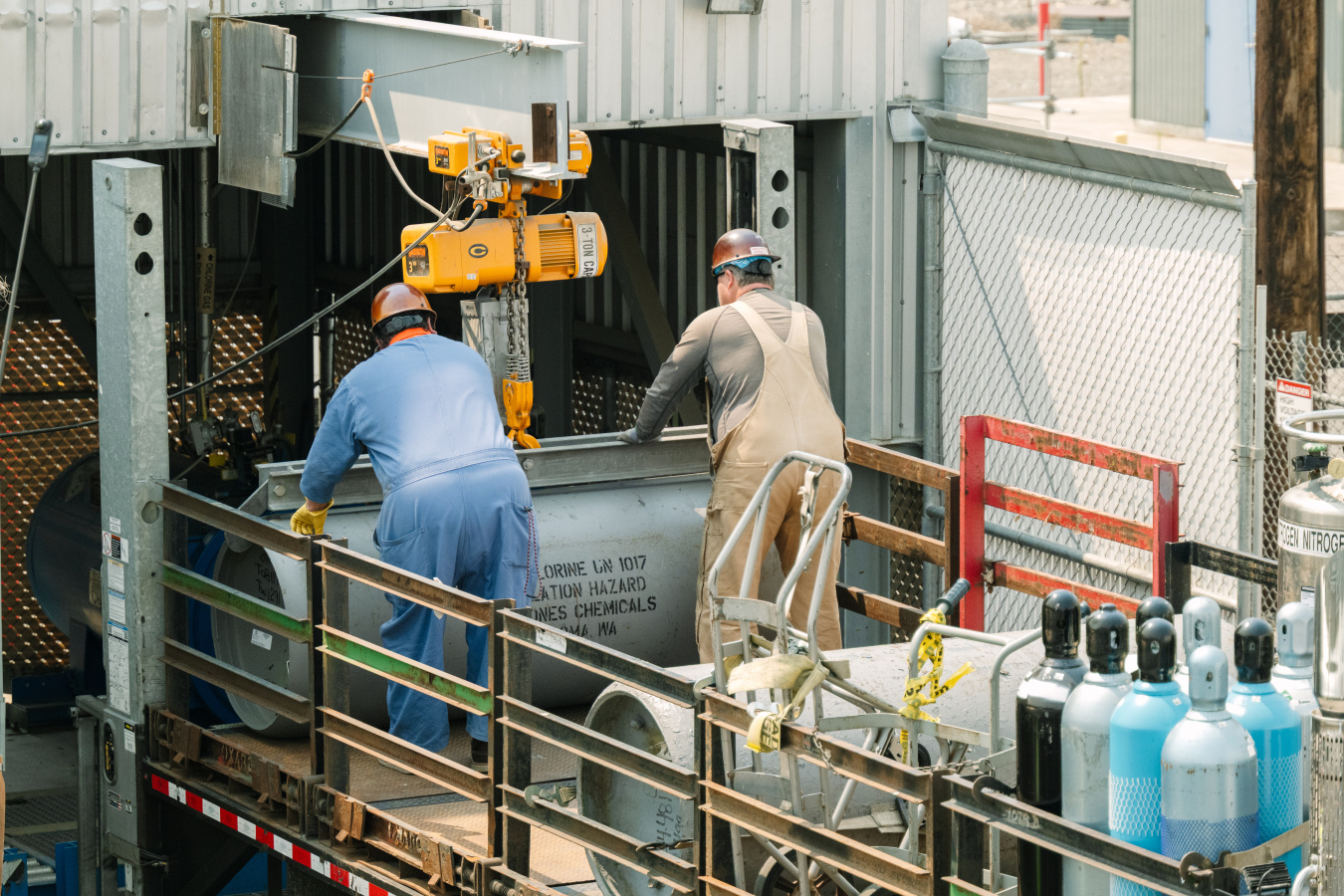 Two employees pushing a large grey canister 