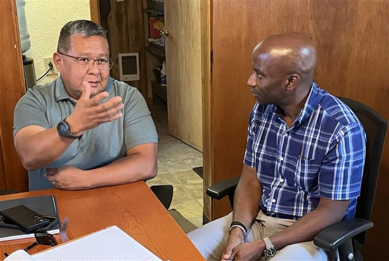 Two professionals sitting at a desk speaking with each other 