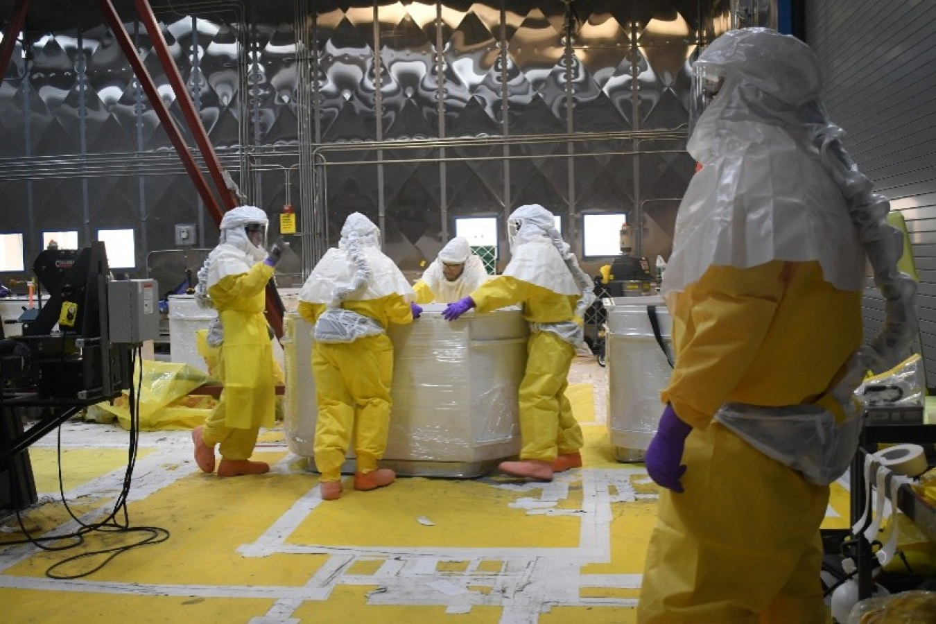 A group of employees in yellow hazmat suits working inside a facility building at the Los Alamos National Lab