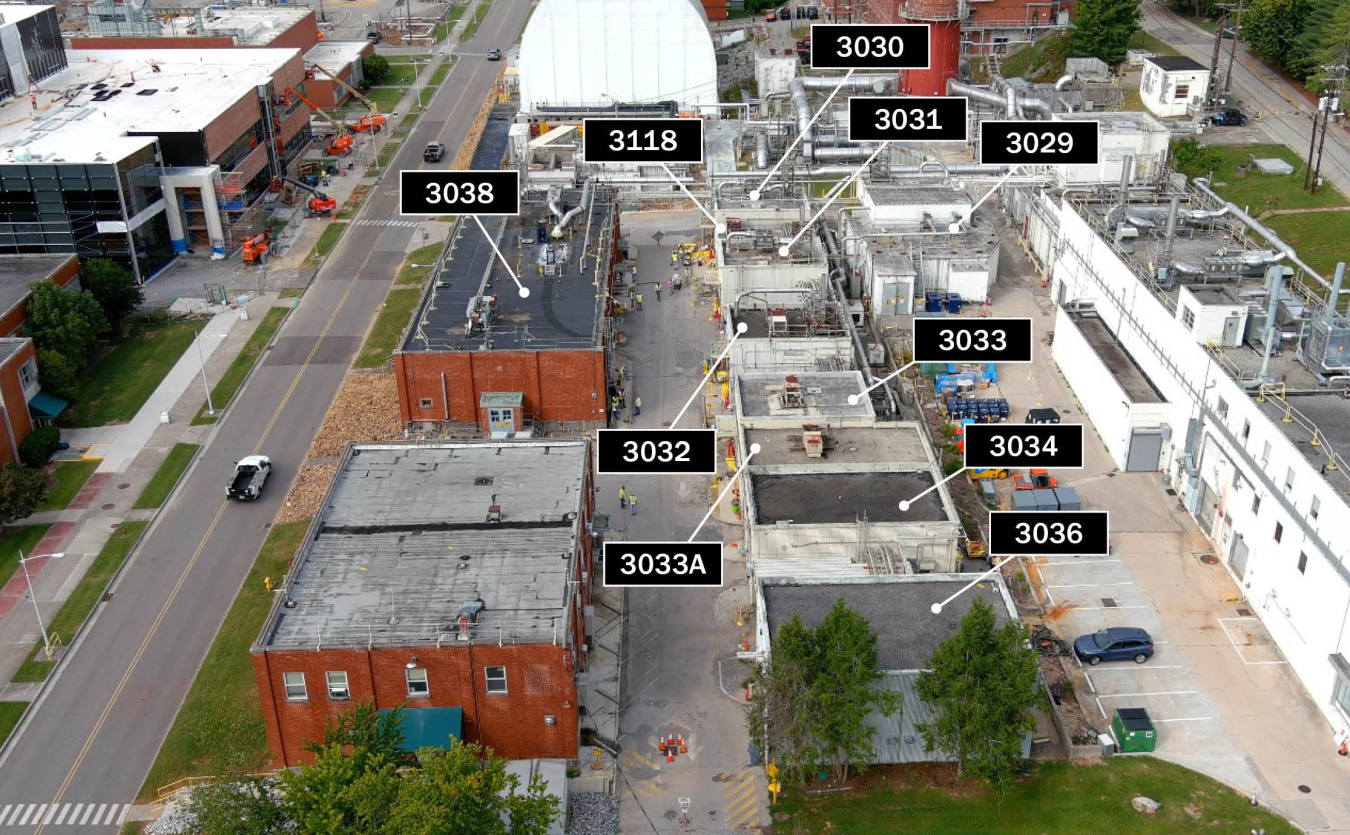 Aerial view of a row of large buildings at the Oak Ridge site labeled by their numbers