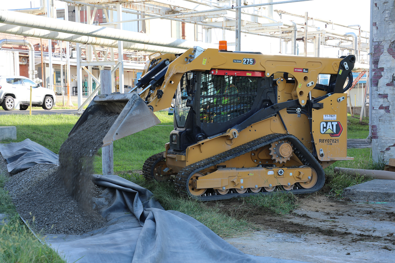 A yellow construction vehicle dumps gravel onto the ground at the Oak Ridge Site during a demolition
