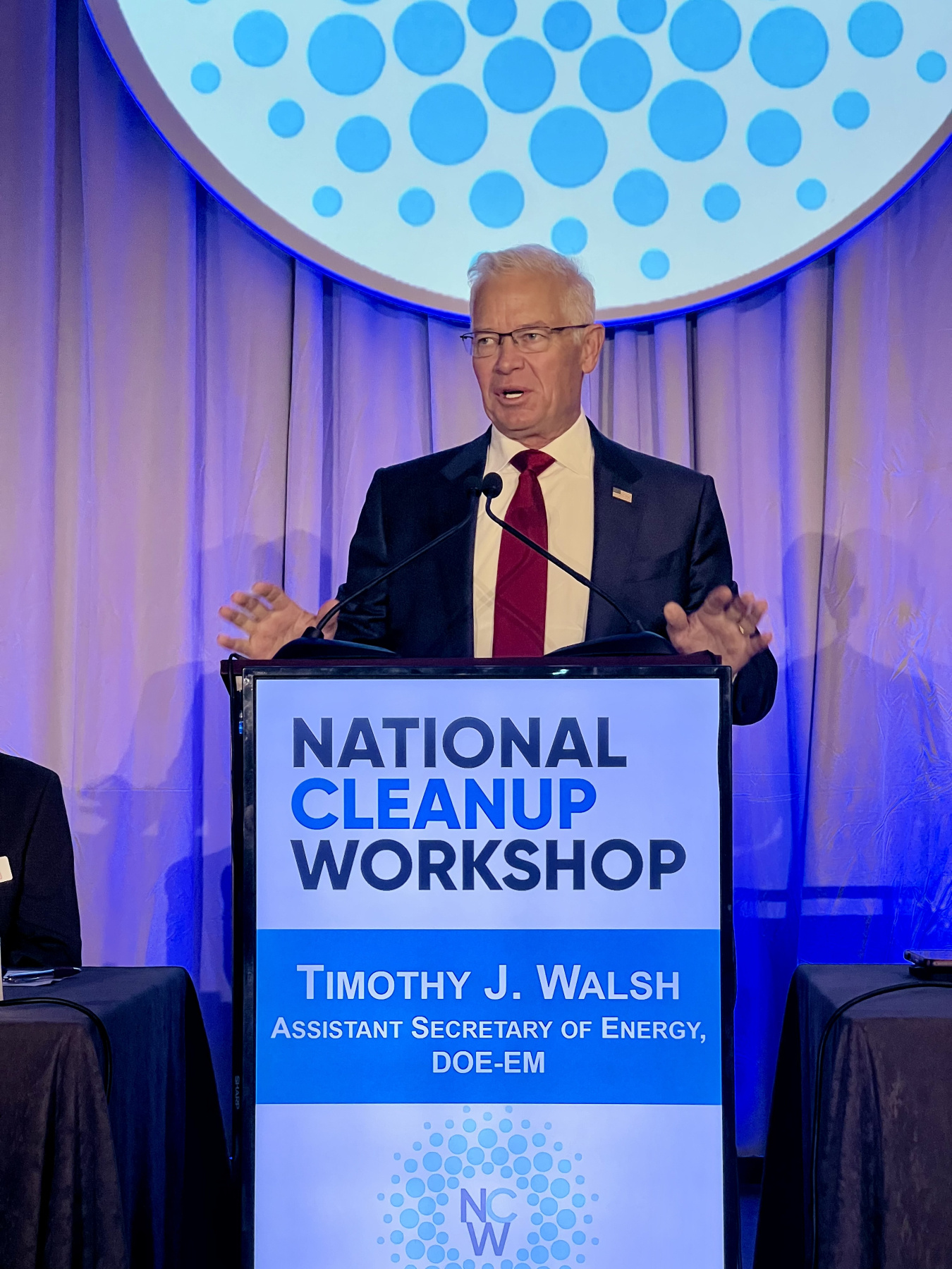EM Assistant Secretary giving a speech on stage behind a podium