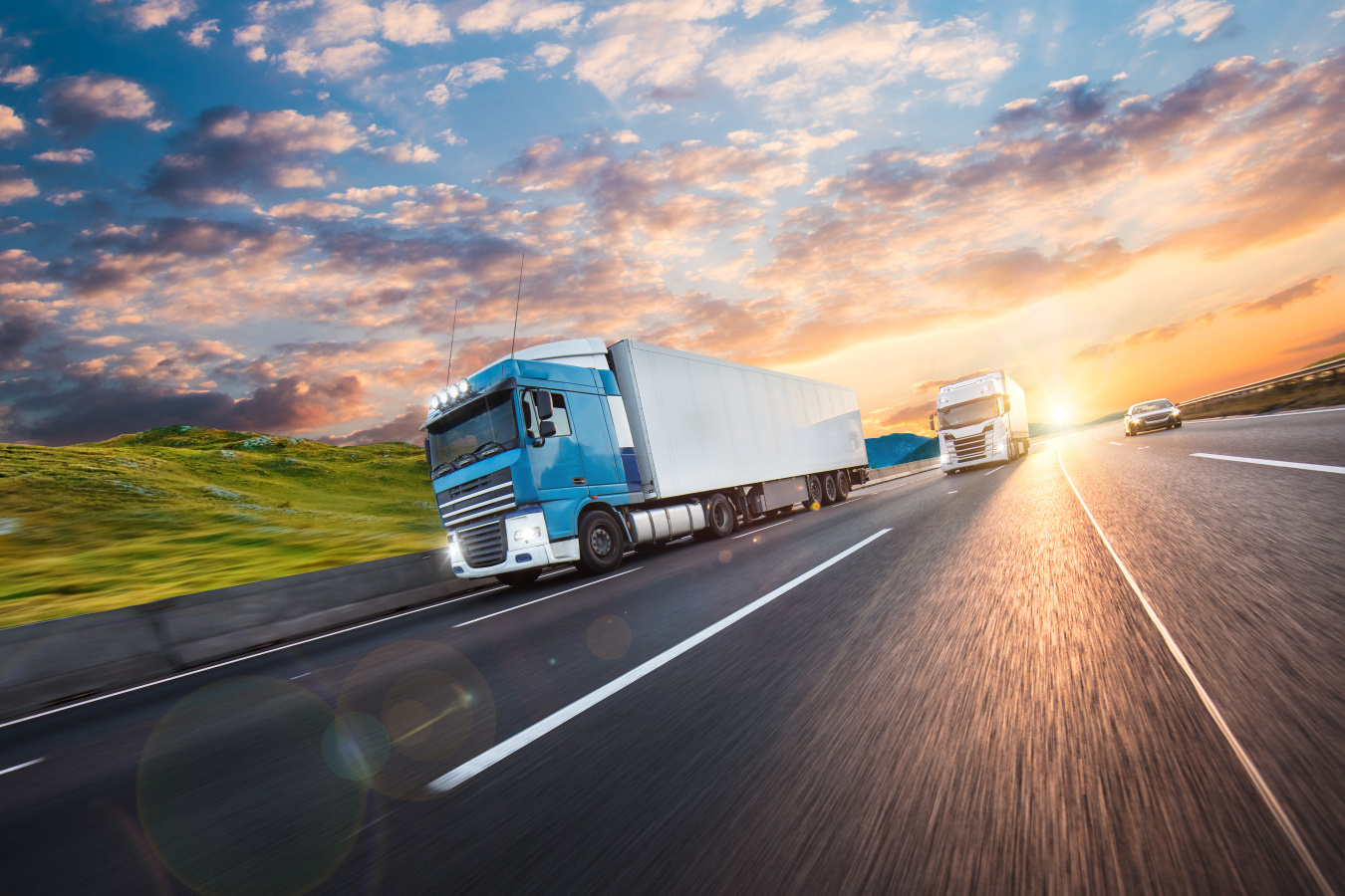 Commercial heavy-duty trucks on a road as the sun is setting