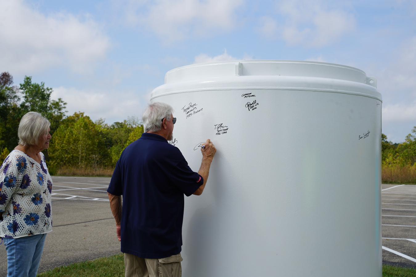 A former worker signs the cargo container; attendees added their signatures to the throwback container to commemorate the 20-year anniversary.