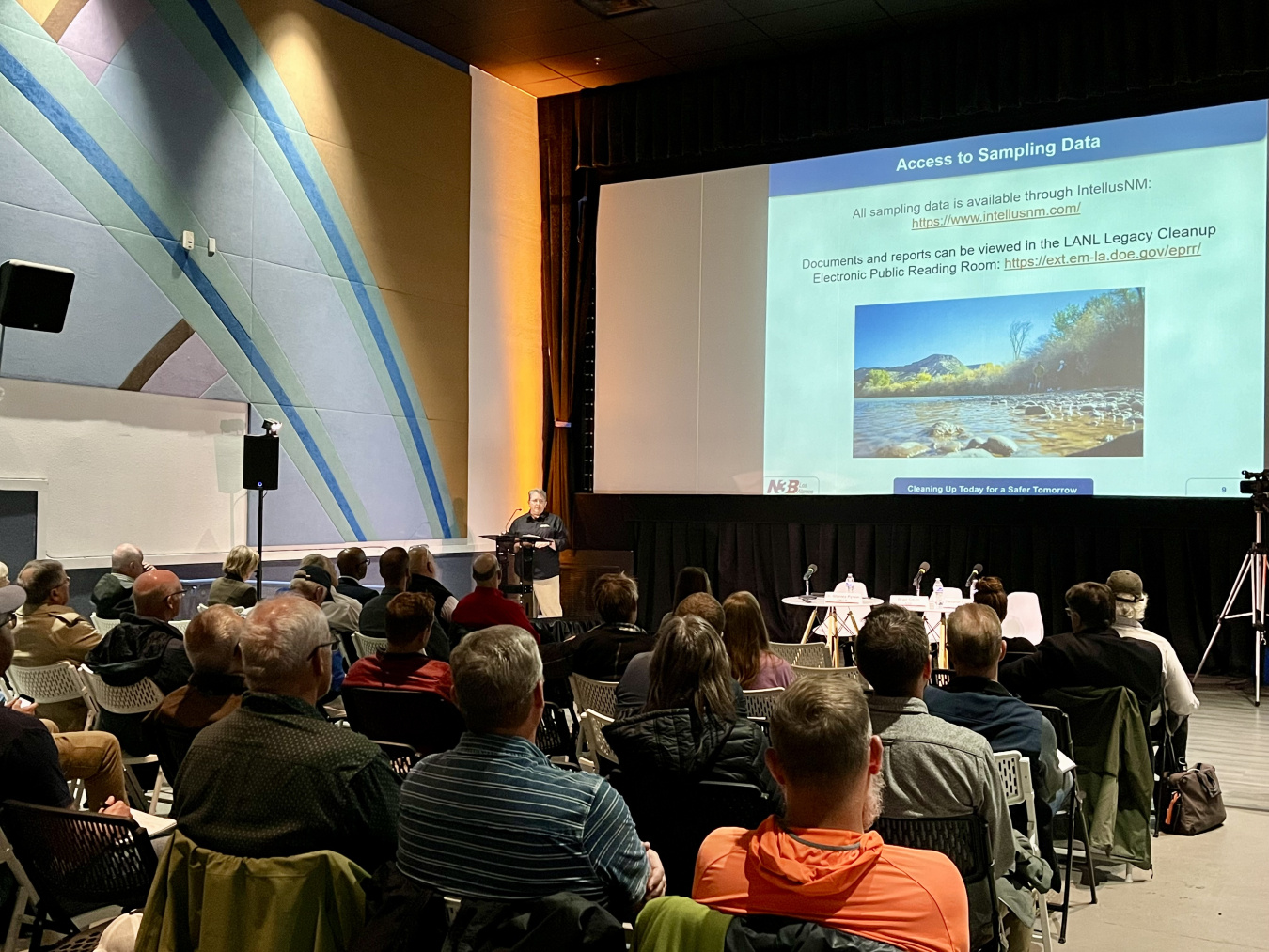An auditorium full of people looking at a presentation on the screen at the front of the room