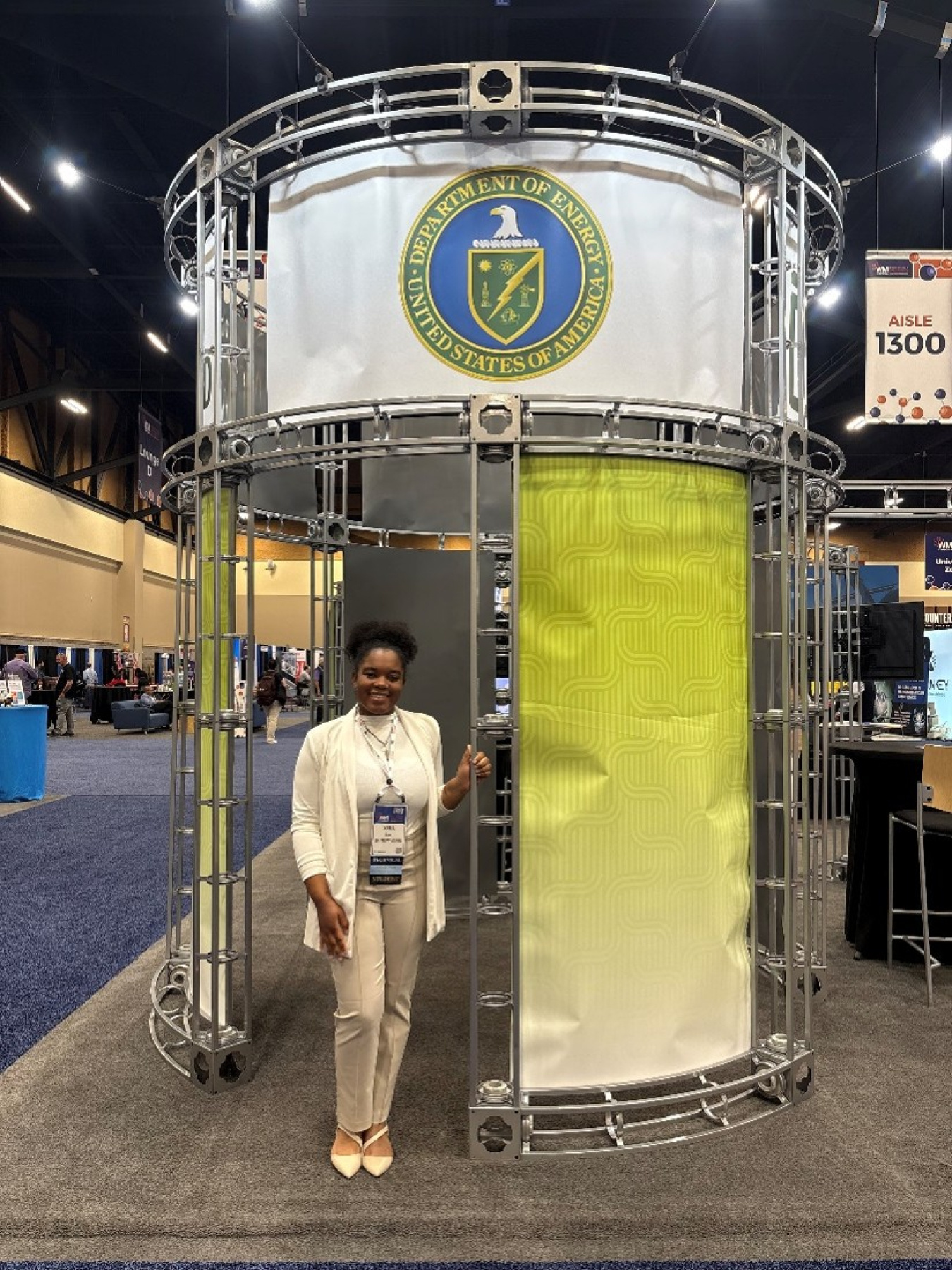 A woman posing for a photo at a conference in a Department of Energy booth