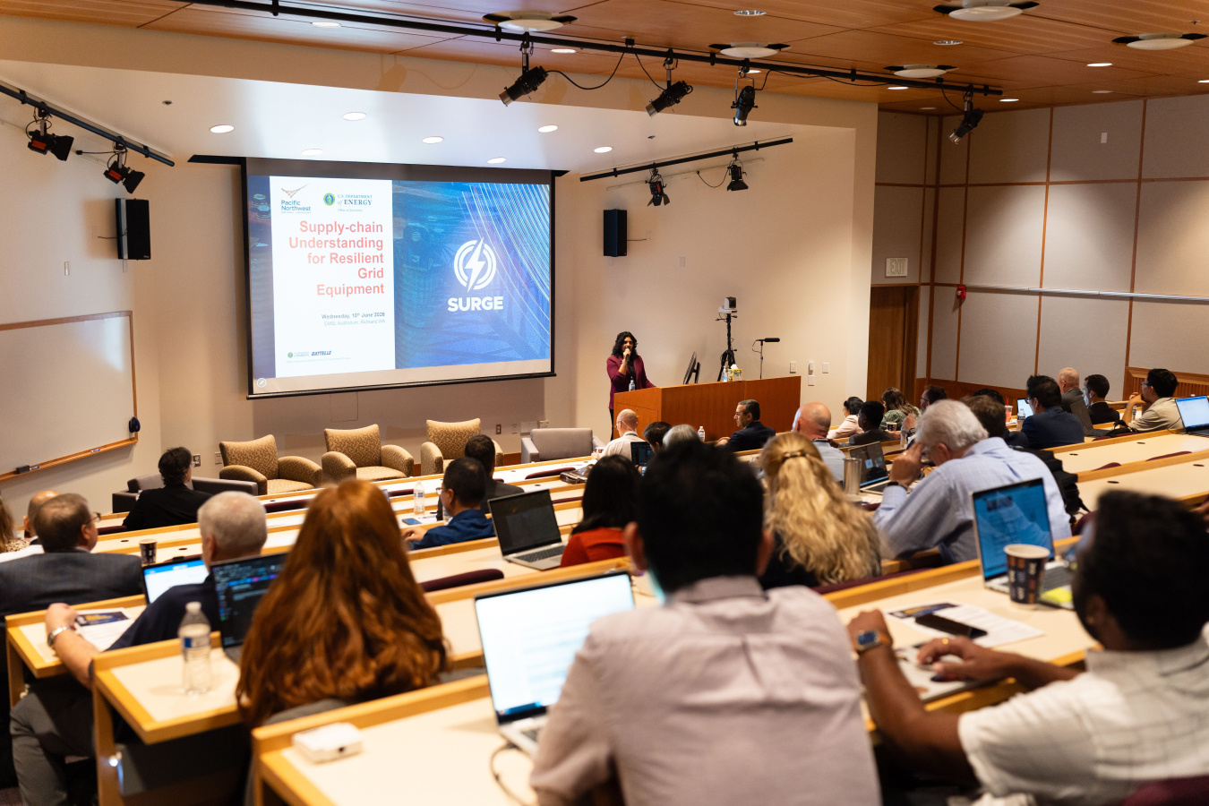 A speaker at the front of the auditorium during a presentation at the SURGE workshop.
