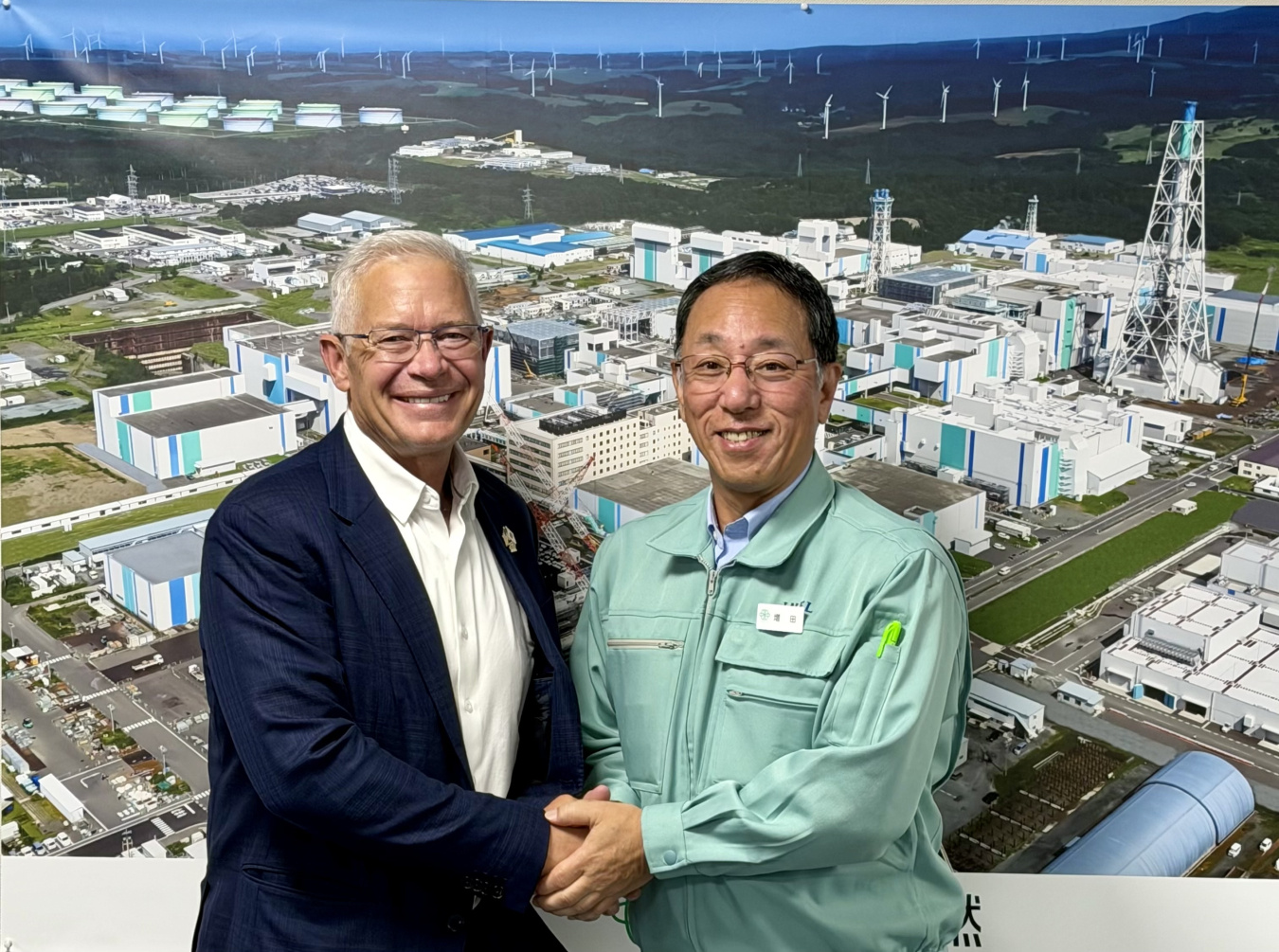 Two professionals pose for a photo together while shaking hands