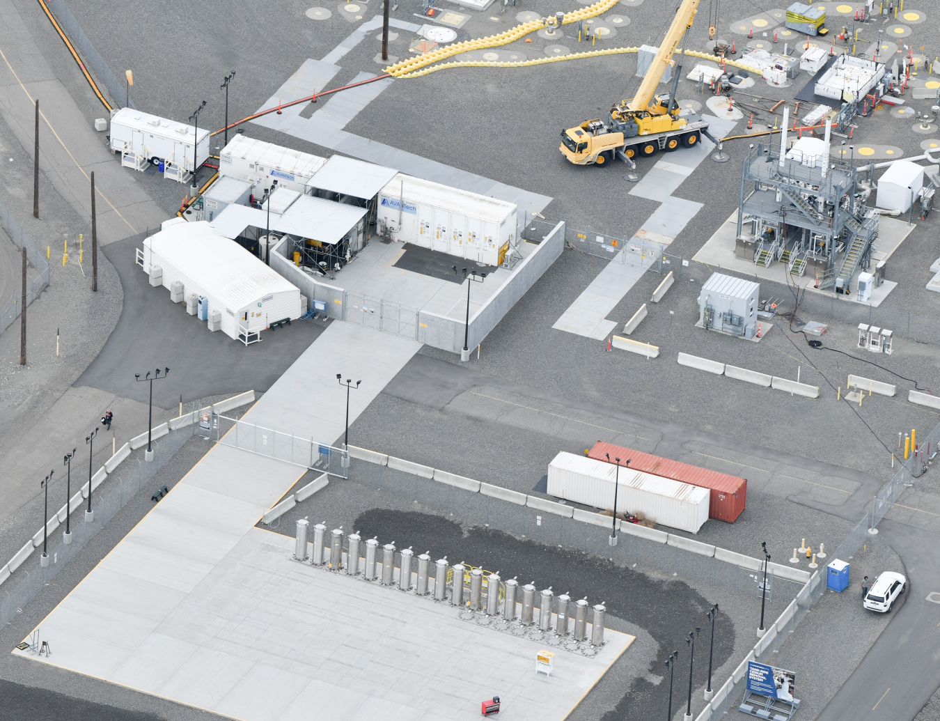Aerial view of a large facility building and storage pads outside of it