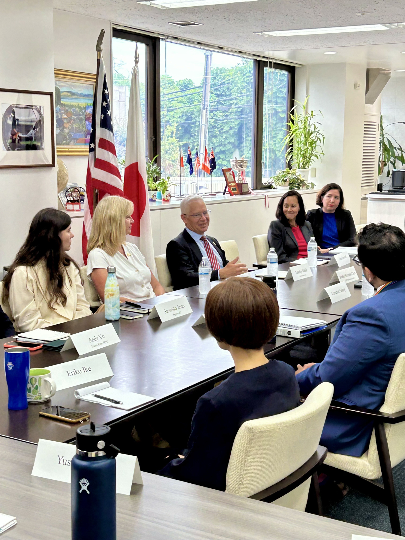 EM Leadership and others sit at a conference table and speak with each other