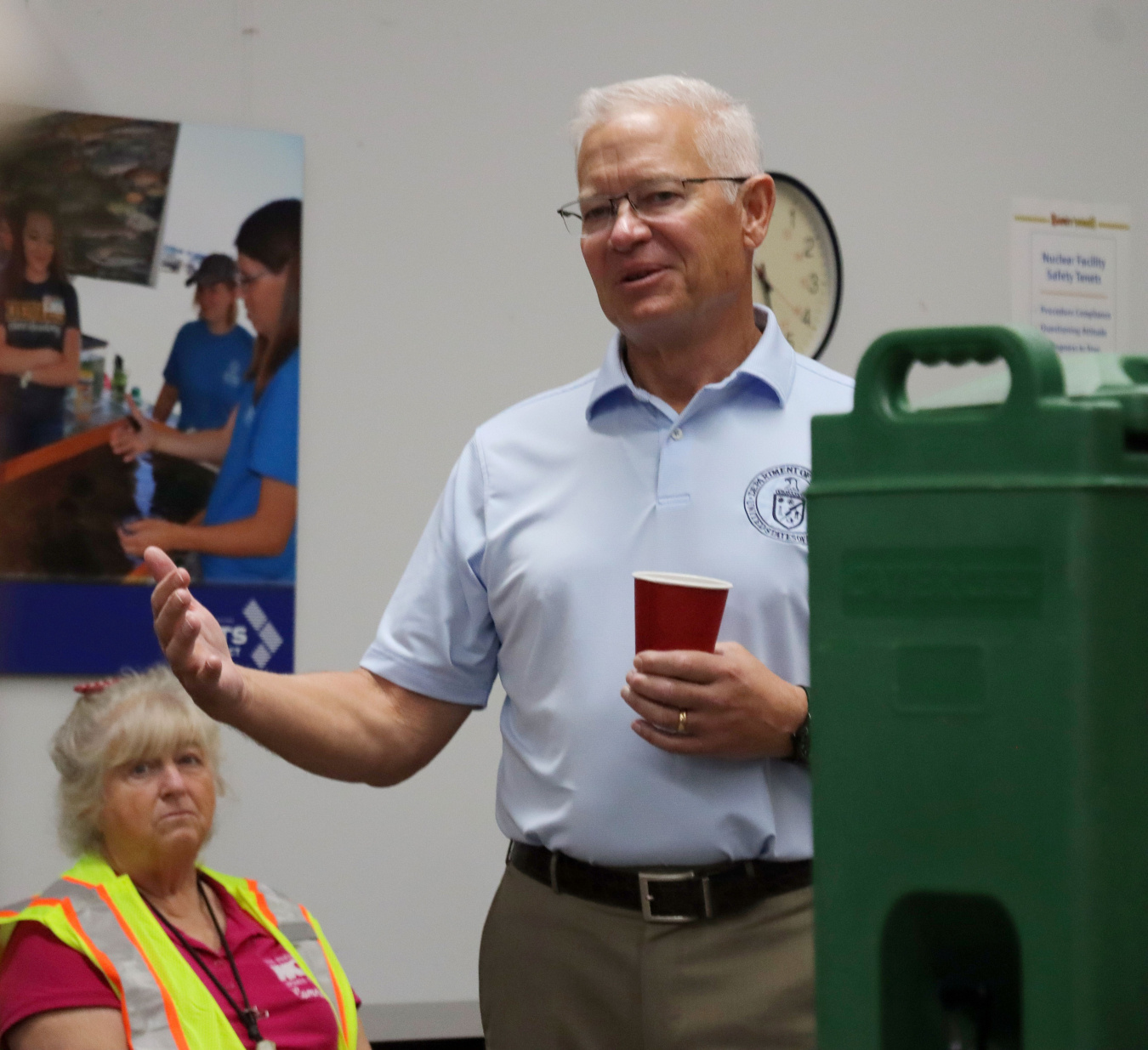 DOE leadership in a light blue shirt stands in a room and speaks to people