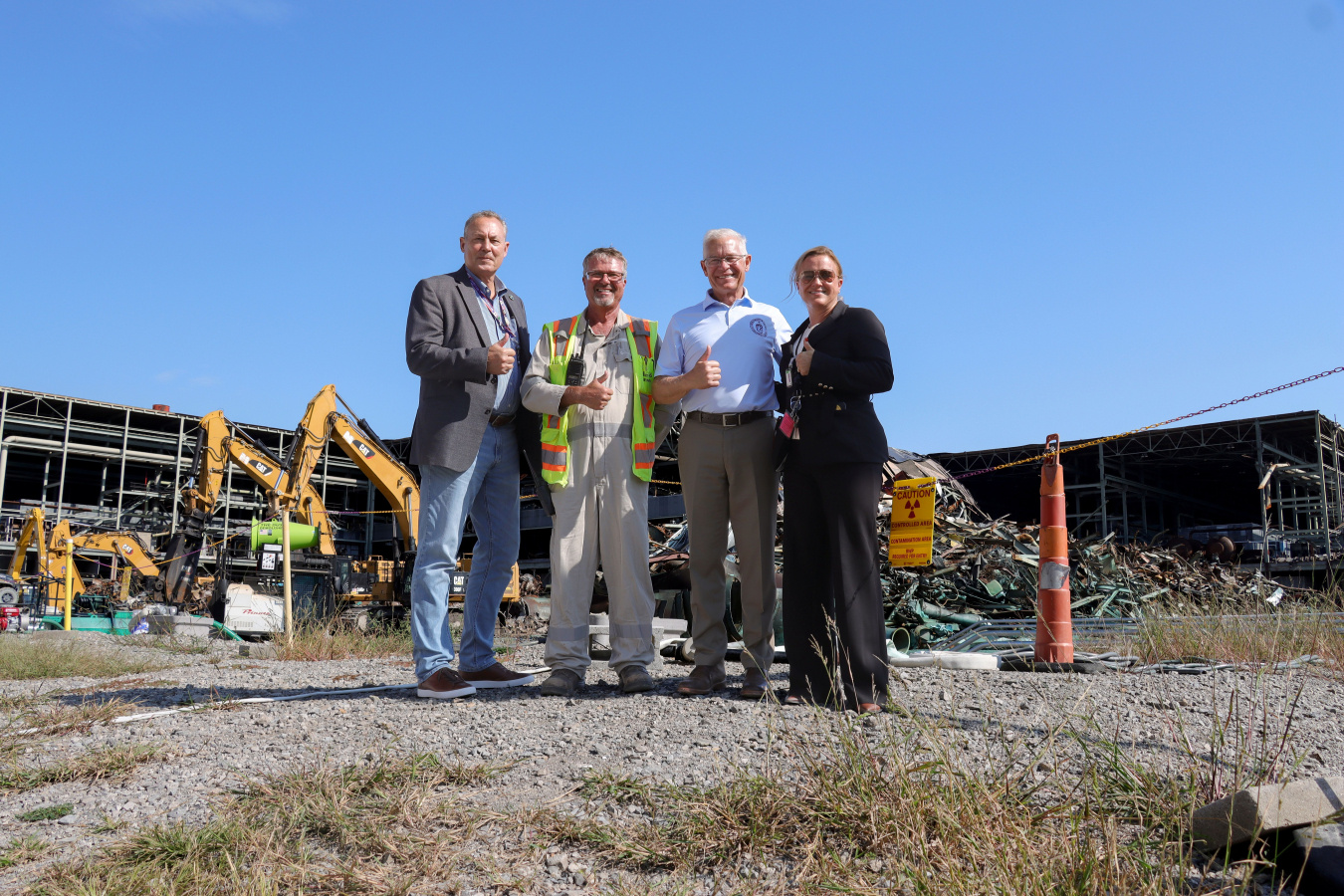 A group of professionals posing for a photo in front of a building demolition site