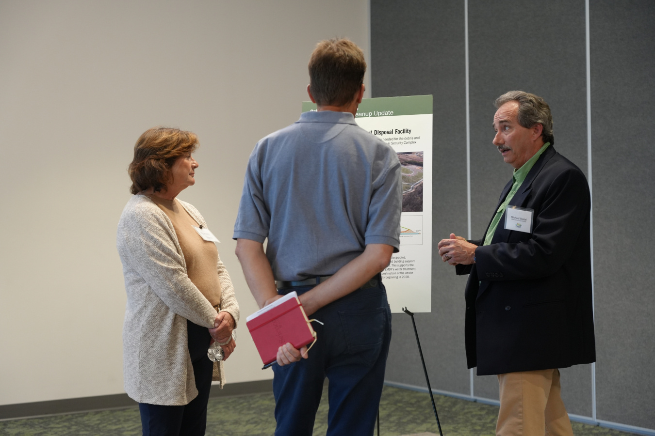 Three professionals speaking to each other at a poster session