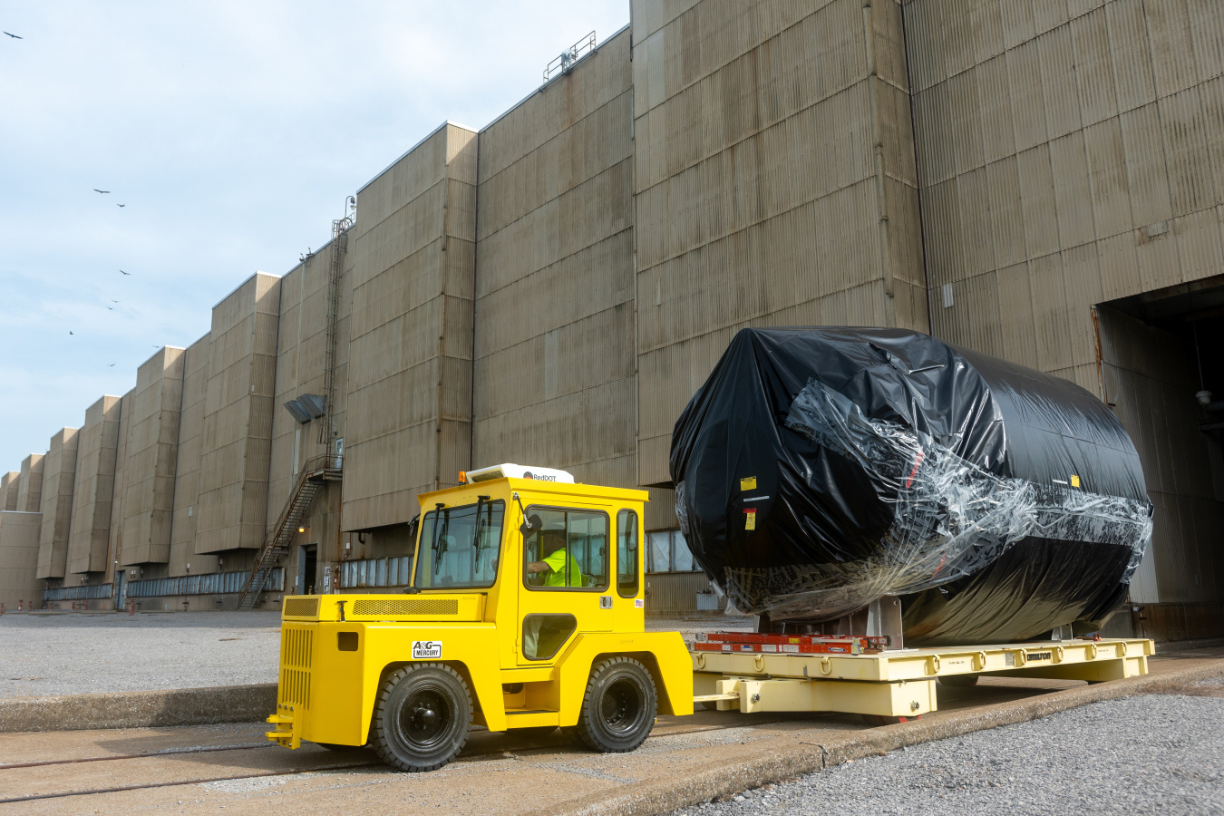A yellow construction vehicle towing a large black circular converter 