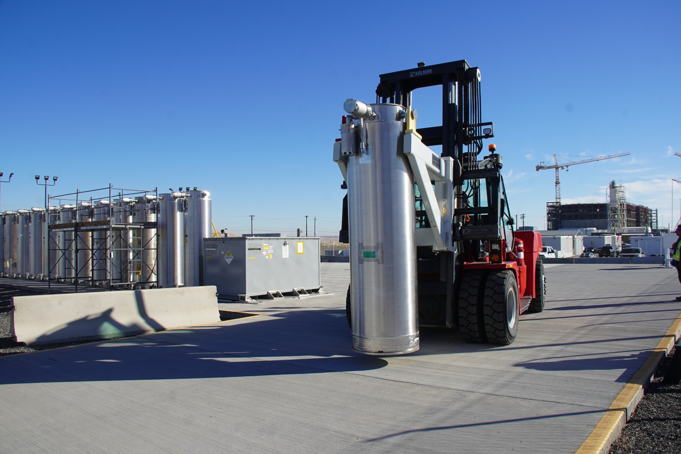 A construction vehicle moving a large metal cylinder 
