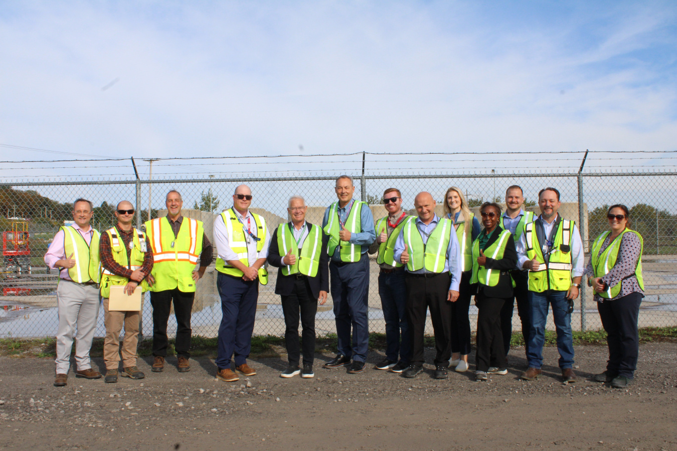 A large group of people in yellow safety vests pose for a photo outside at the West Valley Demonstration Project