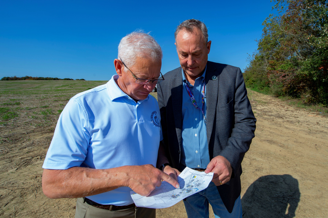 Two members of EM leadership stand outside at the Portsmouth Site and look at a piece of paper