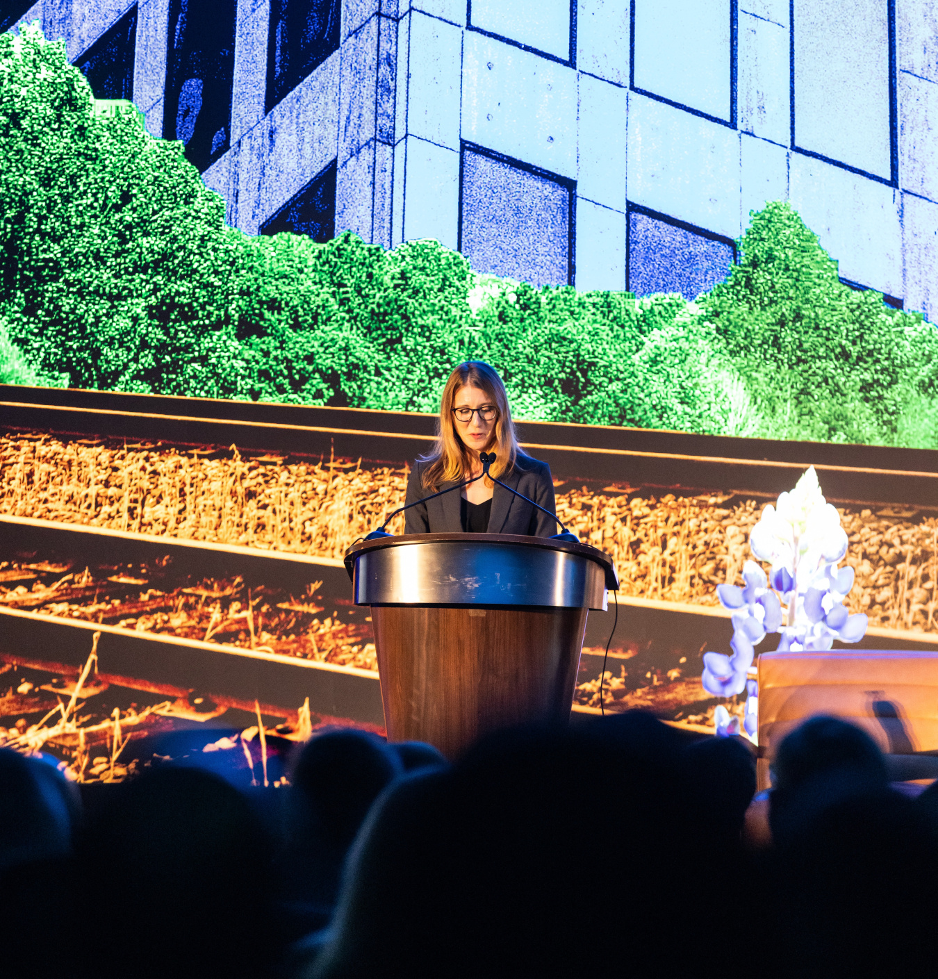 Lauren Boyd standing at a lecturn, giving remarks at the opening plenary.