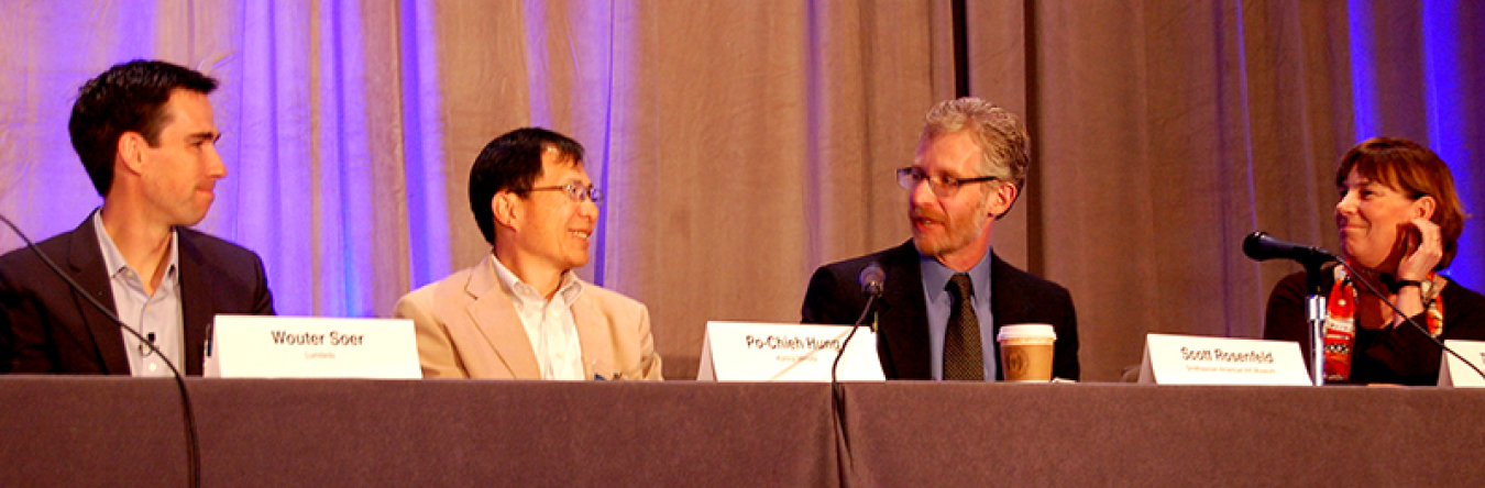 Four people sitting at a table as panelists in front of the audience.