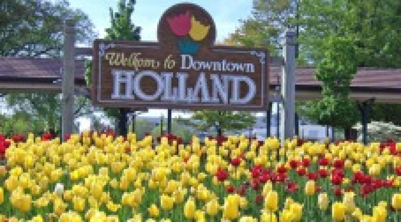 Sign that says "Welcome to downtown Holland," with tulips in the foreground.