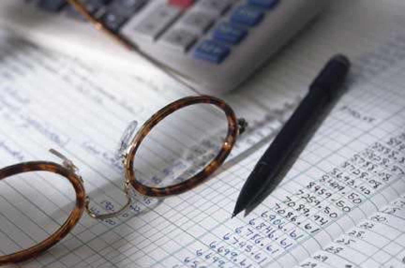 Photo of an accounting sheet, reading glasses and mechanical pencil