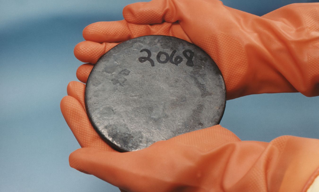 Photo of two gloved hands holding a disc with the number 2068 on it.